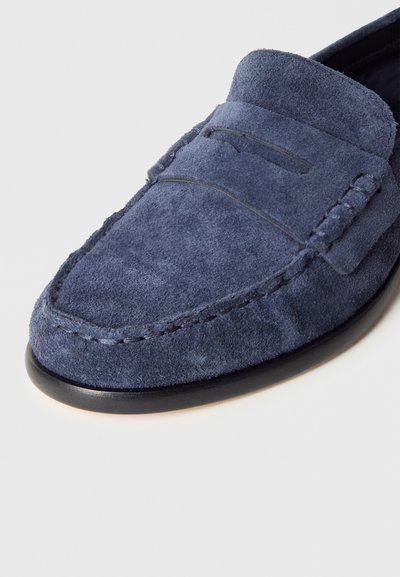 Mokasyny z granatowego zamszu o fakturowanej powierzchni, z kontrastującym przeszyciem i przeszywanym czubkiem, osadzone na czarnej gumowej podeszwie.