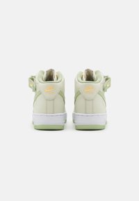 Zapatillas altas Nike Air en verde claro y crema. Material de cuero suave, suela de goma blanca, acentuadas con logo dorado y detalles de correa.