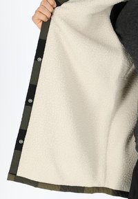 Fleece-lined jacket with a black and olive green check pattern, featuring snap buttons along the edge and a soft, textured interior.