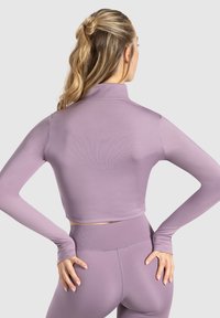 Lavendel crop top med lange ærmer og høj hals. Tætsiddende design, glat tekstur og et subtilt ribbet mønster. Sættes sammen med matchende leggings.