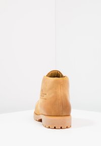 Kohvahitine nahast pahkluu saapad, millel on tekstuuriga viimistlus, kummist põhi ja tugevdatud õmblused. Brändi logo on küljele sisse vajutatud, minimalistlik disain.