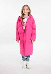 Giacca imbottita rosa brillante con cappuccio, chiusura lampo frontale completa e tasche laterali. Indossata sopra una maglietta a righe e abbinata a jeans azzurri chiari e scarpe bianche.