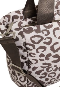 Sac matelassé beige à imprimé léopard marron. Doté de sangles marron solides et de ferrures métalliques. Fermeture zippée en haut.