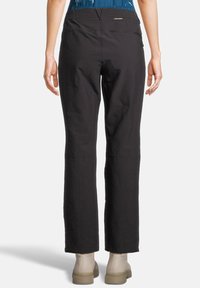 Zwarte broek met een straight-leg design, voorzien van een gladde textuur en een discreet achterzakje. Gepaard met lichtgekleurde enkelboots.