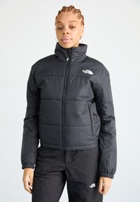 Giacca a vento nera con collo alto e chiusura con zip. Presenta cuciture orizzontali e tasche laterali. Logo sul lato sinistro in alto.