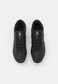Černé tenisky s hladkým koženým svrškem, šněrováním, perforovanými detaily a kontrastní bílou gumovou podrážkou.