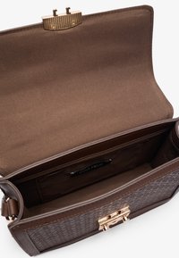 Sac à main marron avec un extérieur texturé, une fermeture en métal doré et un intérieur spacieux doublé de tissu doux avec une étiquette de marque.