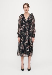 Čierne šaty s kvetinovým vzorom, s volánovým výstrihom a dlhými rukávmi, vyrobené z ľahkého materiálu, s volánovou sukňou a priesvitnou textúrou.