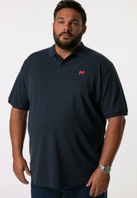 Polo de color azul oscuro con mangas cortas, tapeta de tres botones y un pequeño logotipo rojo "M" en el lado izquierdo del pecho. Fabricado con una tela texturizada.
