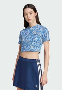 Blue floral-patterned crop top with short sleeves, made of soft material, paired with a dark blue sporty skirt featuring white stripes.