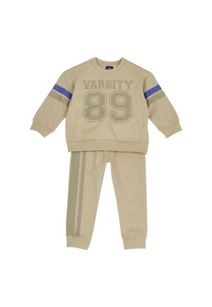 Beigefarbener Kinder-Trainingsanzug mit „VARSITY 89“ auf dem Sweatshirt, mit blauen und grauen Ärmelstreifen und passenden Hosen mit Seitenstreifen.
