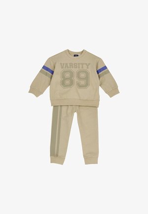 Beige børne træningsdragt med "VARSITY 89" på sweatshirt, med blå og grå ærmestriber og matchende bukser med sidestriber.