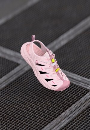 Svijetlopinki atletski tenisice s teksturiranim dizajnom, izrezanim dijelovima i kontrastnim crnim akcentima. Imaju podesive vezice i stražnji povlačni trak.