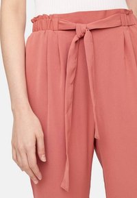 Rosarosa, lätta byxor med smockad midja och knytframsdettalj. Veck sträcker sig från midjan och skapar en avslappnad passform.