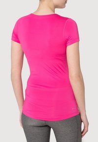 Fitted, short-sleeve t-shirt in bright pink, made from smooth, stretchy fabric with rounded neckline and "DRI-FIT" print near the hem.