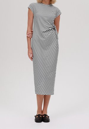 Midi sukienka w czarno-białe paski z krótkimi rękawami typu cap, zawiązywana w talii i dopasowanym krojem. Noszona z czarnymi butami.