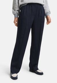 Pantaloni navy con una vestibilità rilassata, realizzati in tessuto morbido, con un cintura elastica, due pieghe anteriori e una texture liscia.