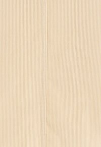 Tissu en velours côtelé beige présentant des côtes verticales. La texture est douce et tactile, avec un léger éclat et des lignes de couture visibles.