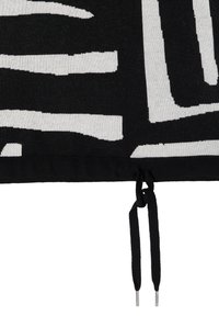 Czarna i biała tkana tkanina z abstrakcyjnym wzorem. Posiada zapięcie na sznurek z metalowymi końcówkami, co nadaje teksturowany wygląd.