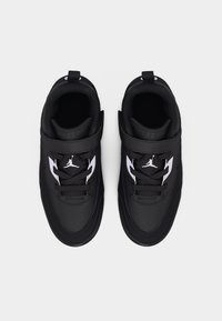Μαύρα παιδικά αθλητικά παπούτσια με λευκό λογότυπο Jumpman, με κορδόνια και λουράκι με Velcro, απεικονιζόμενα από πάνω σε απλό φόντο.