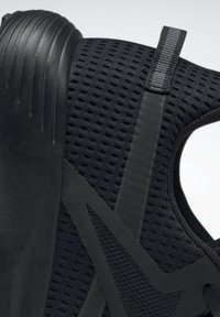 Černá sportovní obuv s texturovaným síťovaným svrškem, hladkými detaily a pevnou gumovou podrážkou, se zesílenou patou a podpůrným designem.