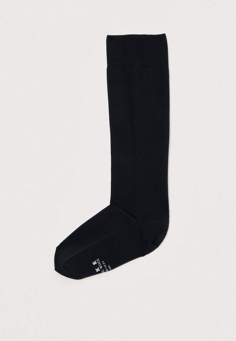 Ciorap negru până la genunchi, confecționat dintr-un material texturat. Prezintă un vârf ribborat și un vârf întărit, cu un mic detaliu logo lângă talpă.