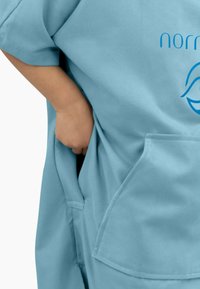 Blaues Kleidungsstück mit kurzen Ärmeln, das eine Tasche an der Seite aufweist. Das Material wirkt weich und strukturiert, mit einem aufgedruckten Logo auf dem Stoff.