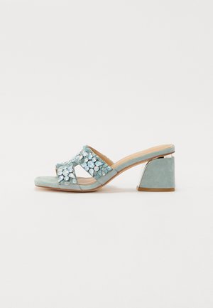 Mules en daim vert menthe avec un design découpé, embellis de gemmes transparentes et irisées sur le dessus, présentant un talon carré.