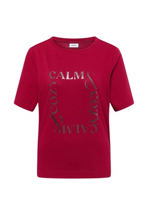 Červené bavlněné tričko s krátkými rukávy a kulatým výstřihem, s metalickým stříbrným textem "CALM & COZY" uspořádaným v zajímavém vzoru.