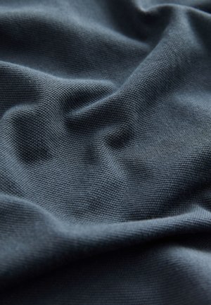 Mørkegråt stof med tekstureret vævning, tydelige rynker og blød overflade. Nærbillede fremhæver materialet og dybden.