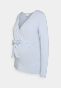 T-shirt de maternidade de manga longa azul claro com um design cruzado e detalhe de laço na cintura. Feita de material macio e elástico.