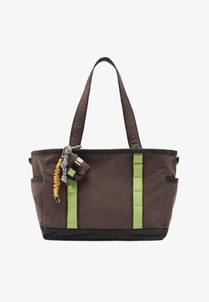 Brązowa torba materiałowa z zielonymi akcentami, wyposażona w dwa długie uchwyty, boczne kieszenie oraz ozdobny brelok przyczepiony.