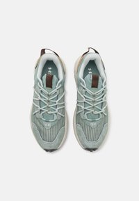 Scarpe sportive verde chiaro con tomaia in tessuto testurizzato, punta rinforzata e accenti beige a contrasto. Presentano lacci tondi e un tirante.