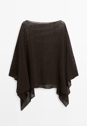 Lockerer schwarzer gestrickter Poncho mit weiten Ärmeln und einem strukturierten offenen Strickmuster, der vor einem weißen Hintergrund hängt.