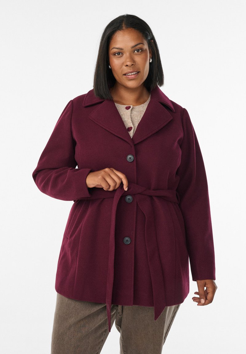 Burgundy coat with large collar and a belted waist, featuring prominent black buttons and long sleeves, made of a soft, textured fabric.