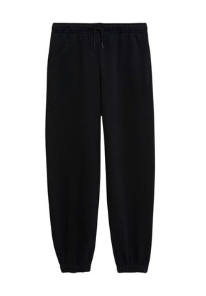 Sort lynlåstrøje med hætte og matchende bukser i blødt materiale, kombineret med grå t-shirt og hvide sneakers med gummisåler.