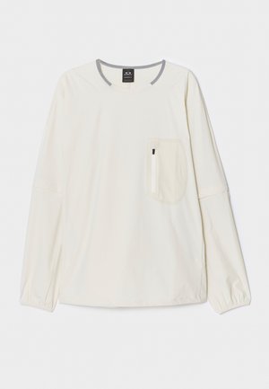 Hosszú ujjú, világos bézs anyagú ing szürke nyakkivágással és díszítéssel. Elöl egy mellzseb található cipzáros zárással. Puha tapintású.