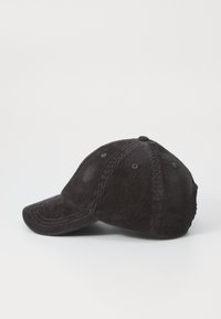 Black corduroy baseball cap with a curved brim, six panels, and ventilation eyelets. Shows textured fabric with ribbed patterns.