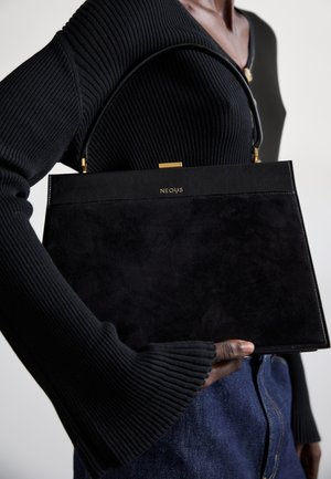 Fekete velúr kézitáska, struktúrált formával. Arany színű fémrészek a tetején és a "NEOUS" logó. Fekete, testhez simuló bordázott felsővel viselve.