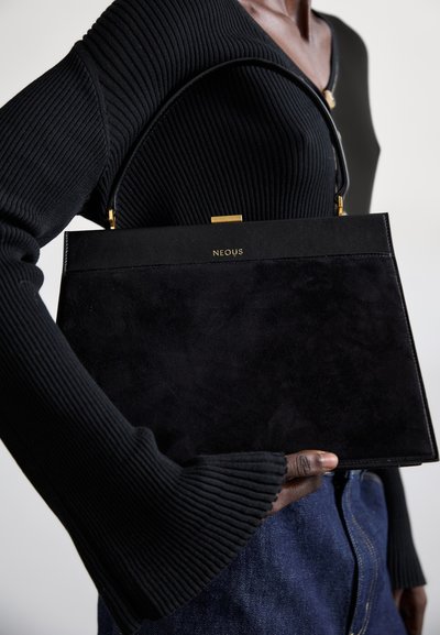 Schwarze Wildlederhandtasche mit strukturiertem Design. Goldfarbene Hardware-Akzente oben und "NEOUS"-Logo. Getragen mit einem enganliegenden, schwarzen Rippoberteil.
