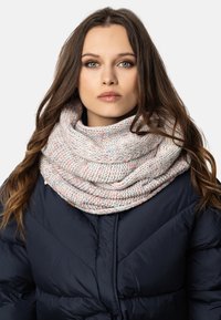 Écharpe en col tricotée en laine douce de couleurs pastel, caractérisée par une texture épaisse et un design superposé, portée sur une doudoune noire.