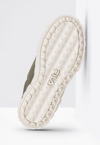 Zelený teniskový svršek s texturou a čistě bílou gumovou podrážkou s vzorovaným protiskluzem a logem Fila vyraženým na boku.