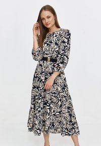 Kwiatowa sukienka midi w kolorze granatowym i kremowym, z długimi rękawami, falbaną u dołu, dopasowaną talią oraz akcentem w postaci złotej klamry.