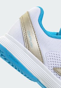 Valge spordijalats hingava võrguga pealisküljel, kuldsed aktsendid, türkiissinised detailid, tekstuurse tallaga ning "ADIDAS" ja "COURTFLASH" logodega.