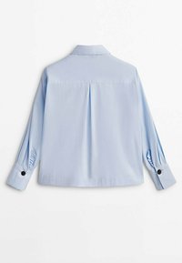 Chemise bleu clair à manches courtes avec col, dos plissé et poignets boutonnés ornés d'accents noirs. Tissu lisse et coupe décontractée.