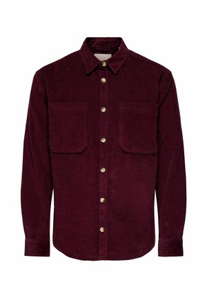 Chemise en velours côtelé rouge foncé à manches longues avec deux poches poitrine à l’avant et une rangée de boutons clairs au centre.