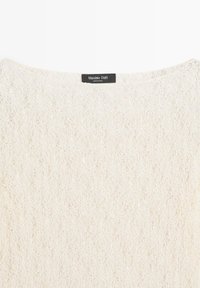 Weißer Strickpullover mit rundem Halsausschnitt und einem schwarzen Etikett mit der Aufschrift "Massimo Dutti, Made in China" im Krageninnenteil.