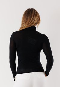 Maglietta nera a maniche lunghe con un design a collo alto. Realizzata in materiale leggero, presenta una silhouette aderente e una texture liscia.