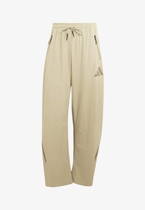 Beige wijde broek met elastische tailleband, trekkoord, ritssluiting aan de zijkanten, en een subtiel logo op de rechterdij.