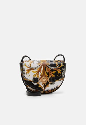 Schwarz-weiße Satteltasche mit kunstvollem gold-braunem barockem Blättermuster und einem goldenen Medusa-Emblem vorne, mit einem schwarzen Riemen.